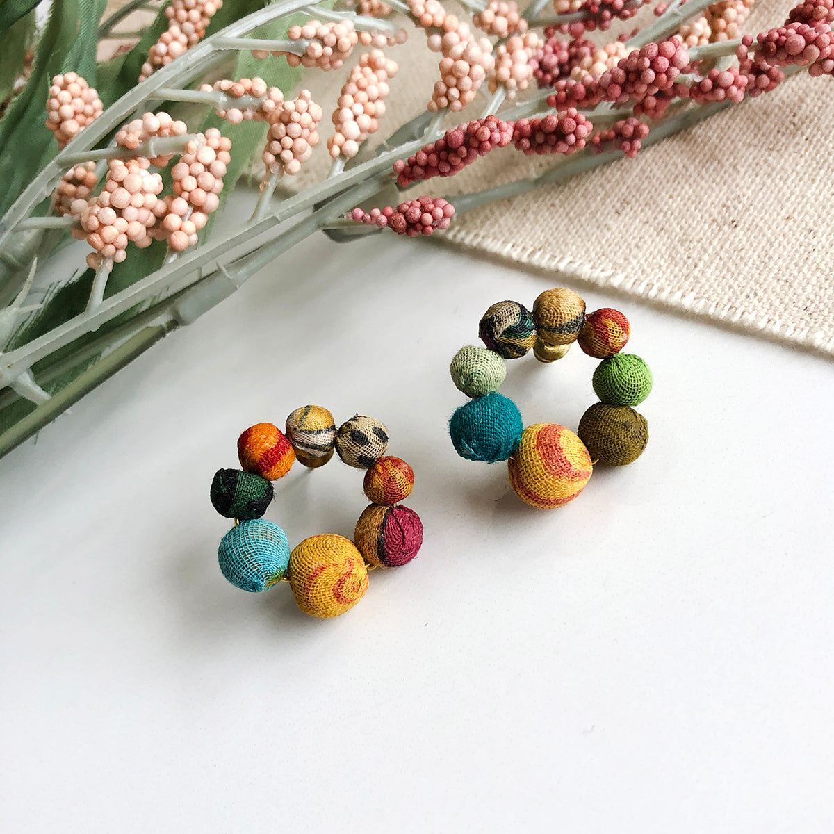 Angelco Accessories kantha ring studs on white flatlay with pink floral background