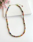 Angelco Accessories single strand kantha medium necklace on flatlay with pink flowers in top left corner