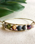 Angelco Accessories Kantha gold bangle on linen surface with green leaf