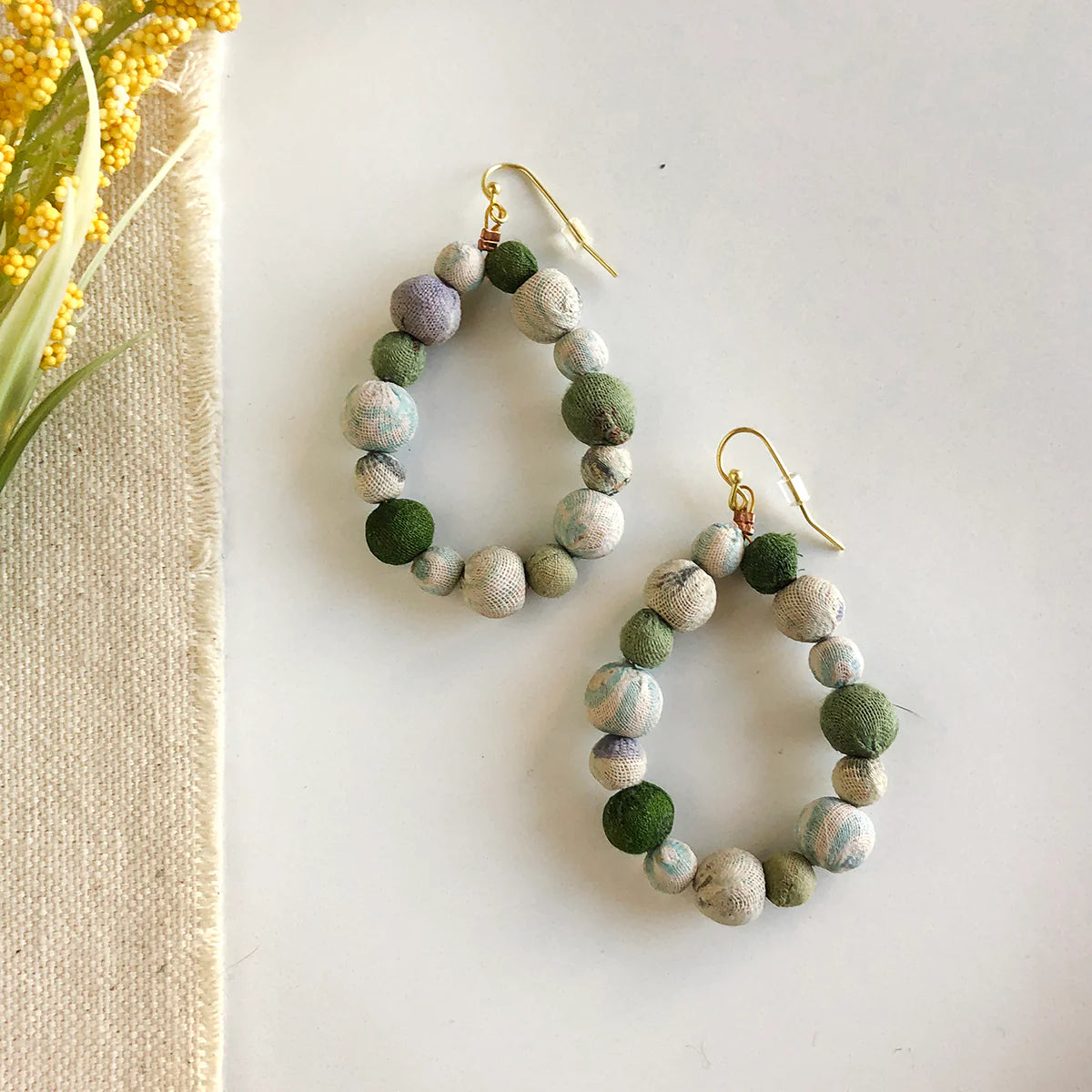 Angelco Accessories Teardrop kantha earrings - sea foam - flatlay with linen and small yellow flower